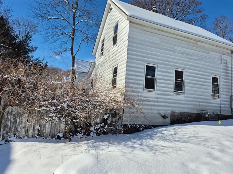 A white house with snow on the ground in front of it