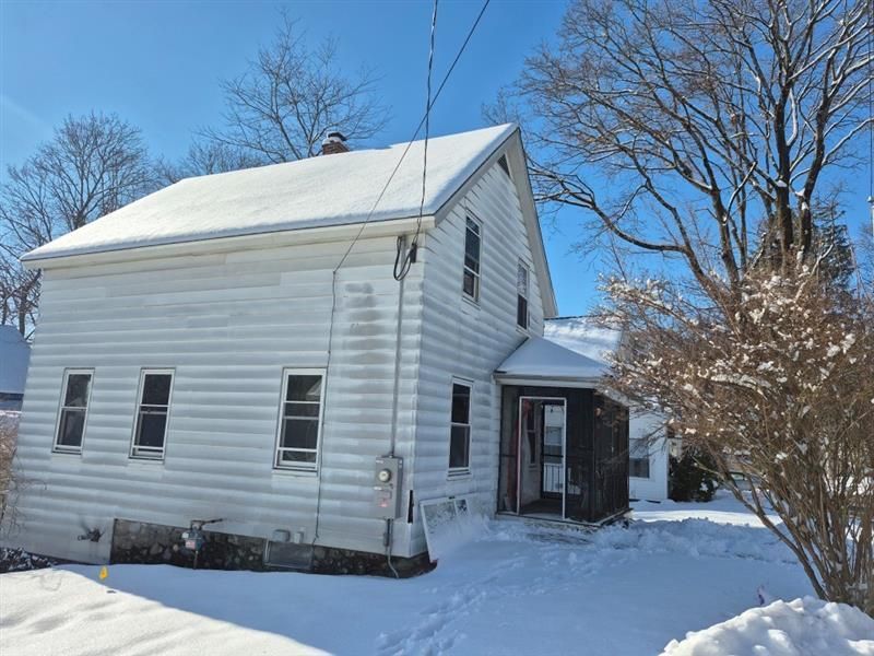 A white house is covered in snow on a sunny day.