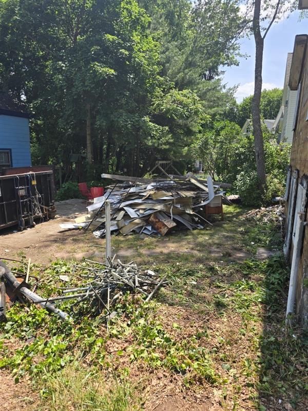 A pile of trash is sitting in the grass in front of a house.