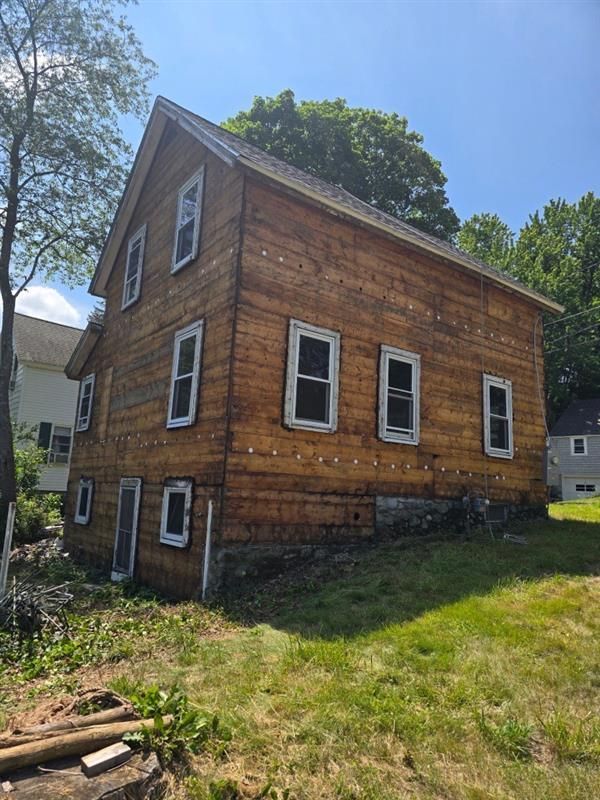 A large wooden house with a lot of windows is sitting in the middle of a grassy field.