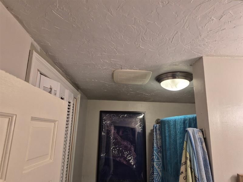 A bathroom with a light on the ceiling and towels hanging on the wall.