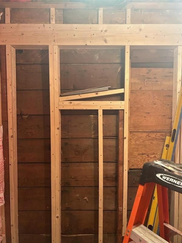 A ladder is sitting in front of a wooden wall.