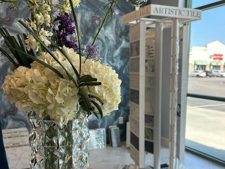Flowers in a vase near a tile display; shop interior with a blue and white patterned wall.