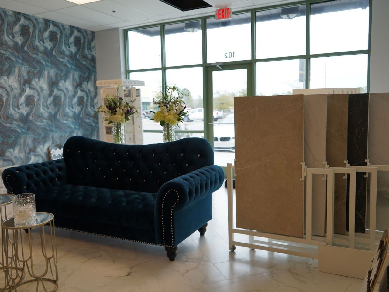 Interior showroom with blue sofa, marble samples, and large windows.