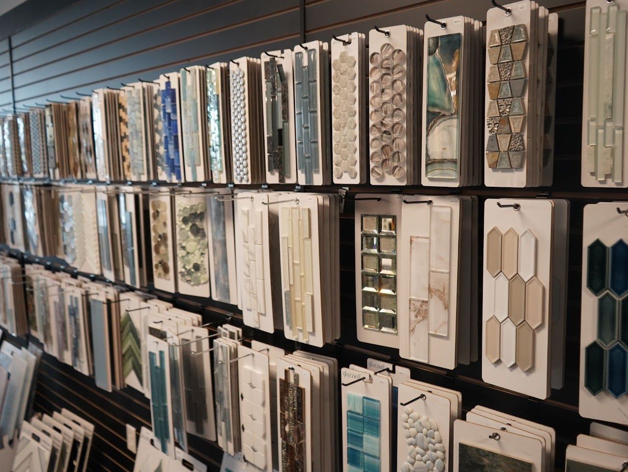 Tile samples displayed on a store wall, various colors and patterns.