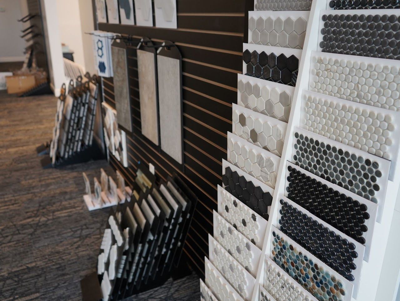 Tile samples displayed on racks in a showroom, various colors and patterns.