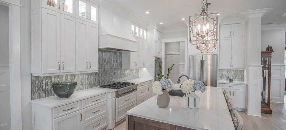 Bright, modern kitchen with white cabinets, large island, and decorative light fixture.