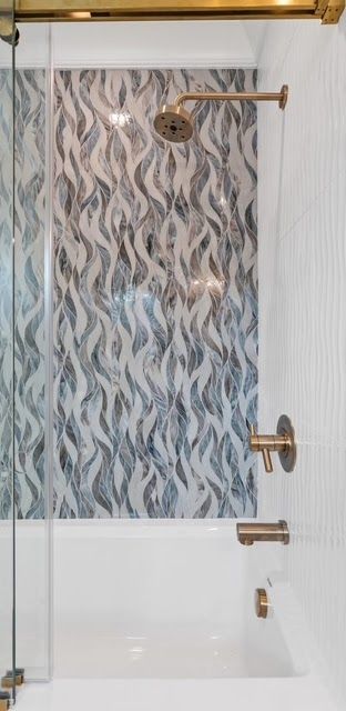 Shower with gold fixtures and patterned tile in a bathroom.