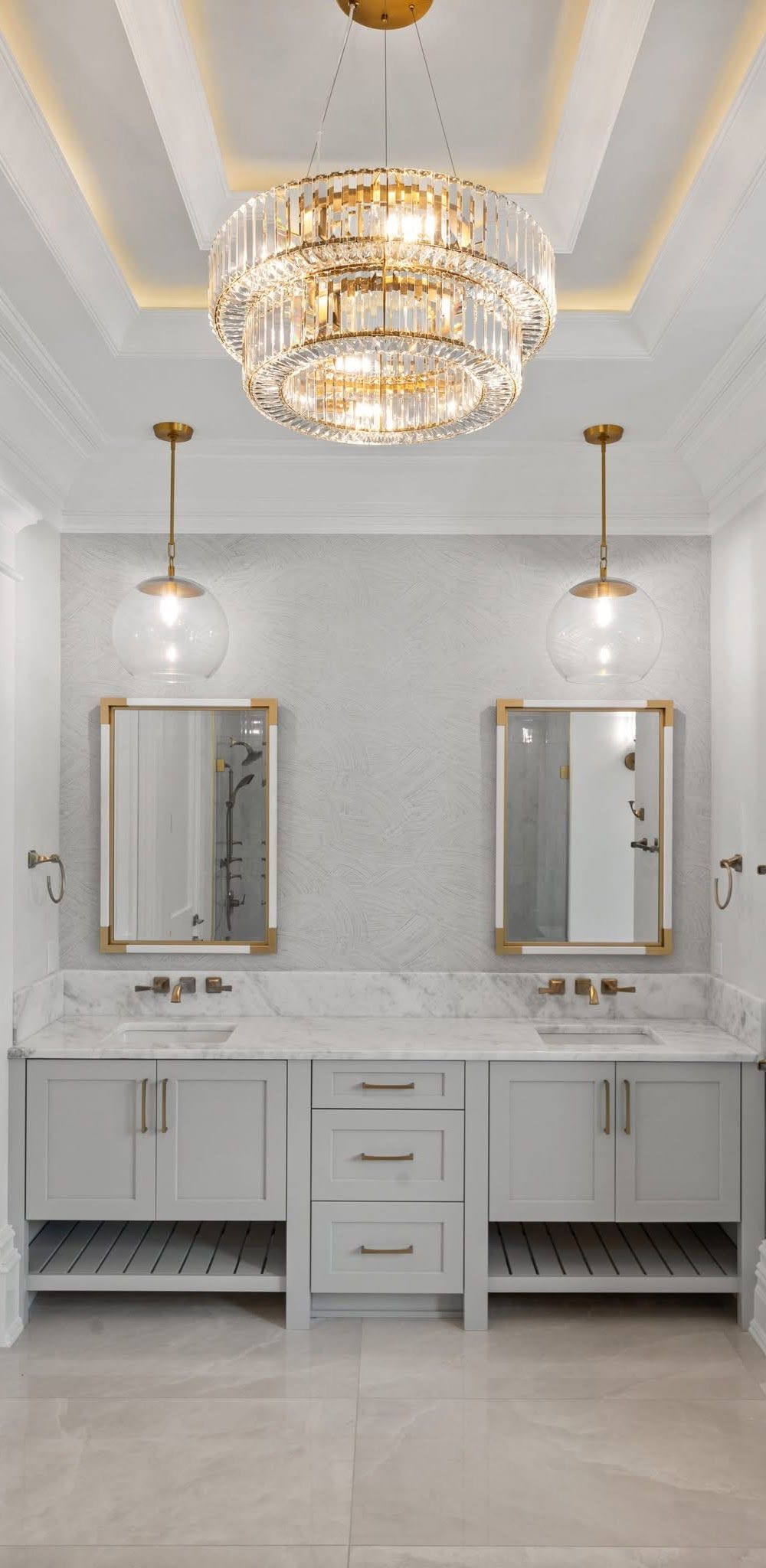 Bathroom with a gray vanity, two mirrors, and a chandelier.