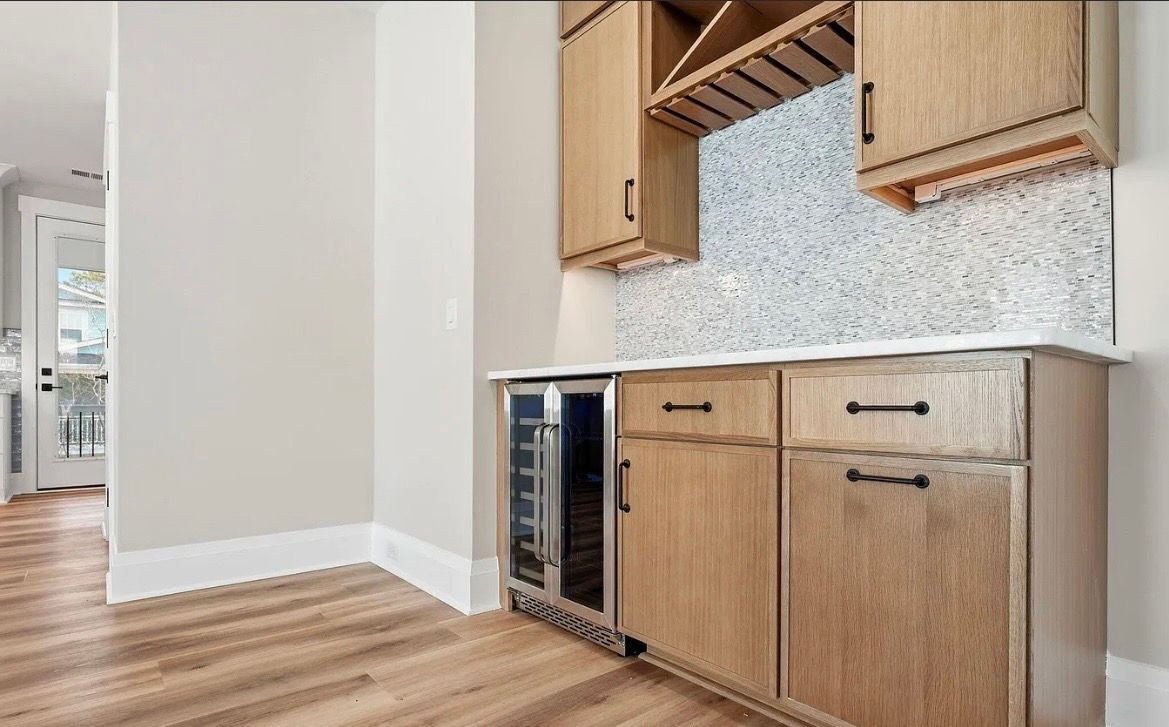 Modern kitchen nook with wood cabinets, speckled tile backsplash, and a built-in wine fridge