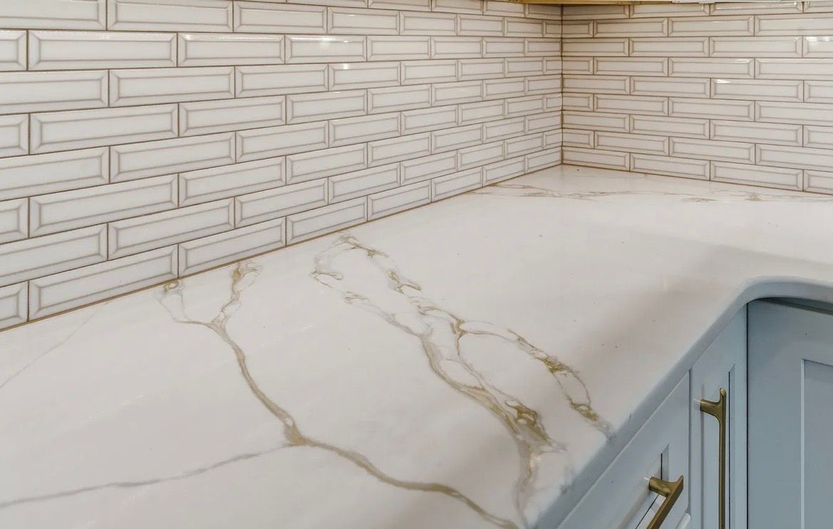 White marble-look kitchen countertop with gold veining and a light tiled backsplash