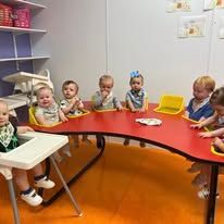 A group of babies are sitting at a table in a room.