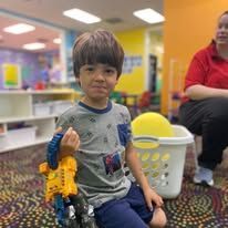 A young boy is sitting in a wheelchair holding a toy robot.