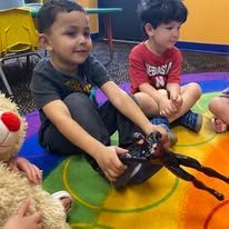 A group of children are sitting on the floor playing with stuffed animals.