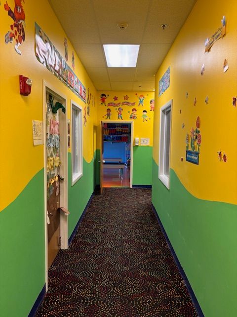 A long hallway with yellow and green walls and a carpet.