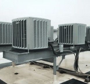 Two grey industrial HVAC condenser units mounted on a metal support platform on a flat rooftop.
