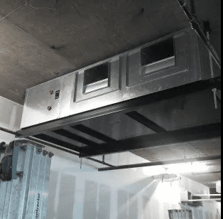 A silver metal HVAC unit suspended from an industrial ceiling above a room under construction.