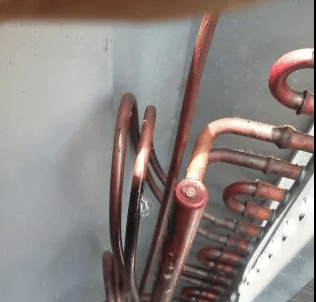 Copper tubing and U-bend connectors on an industrial HVAC cooling coil unit.