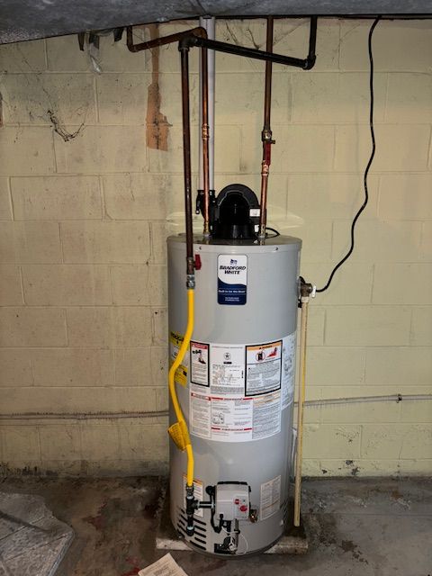 A natural gas water heater in a basement.  Copper and yellow gas lines with black exhaust piping.