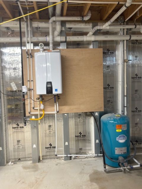 Water heater and pressure tank installed in a utility room with exposed plumbing.