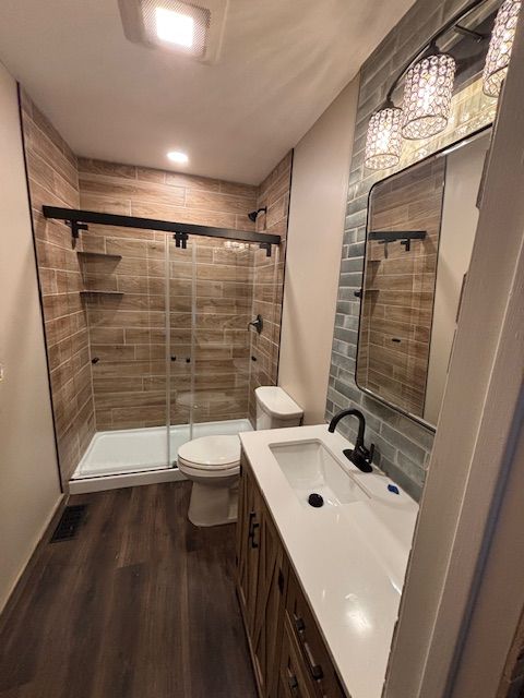 Bathroom with wood-look tile shower and vanity, black fixtures, and wood-look flooring.