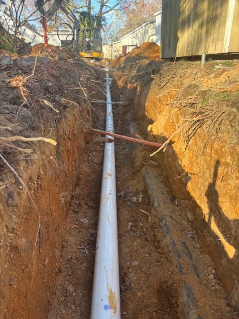 Trench with white pipe, brown soil, construction site.