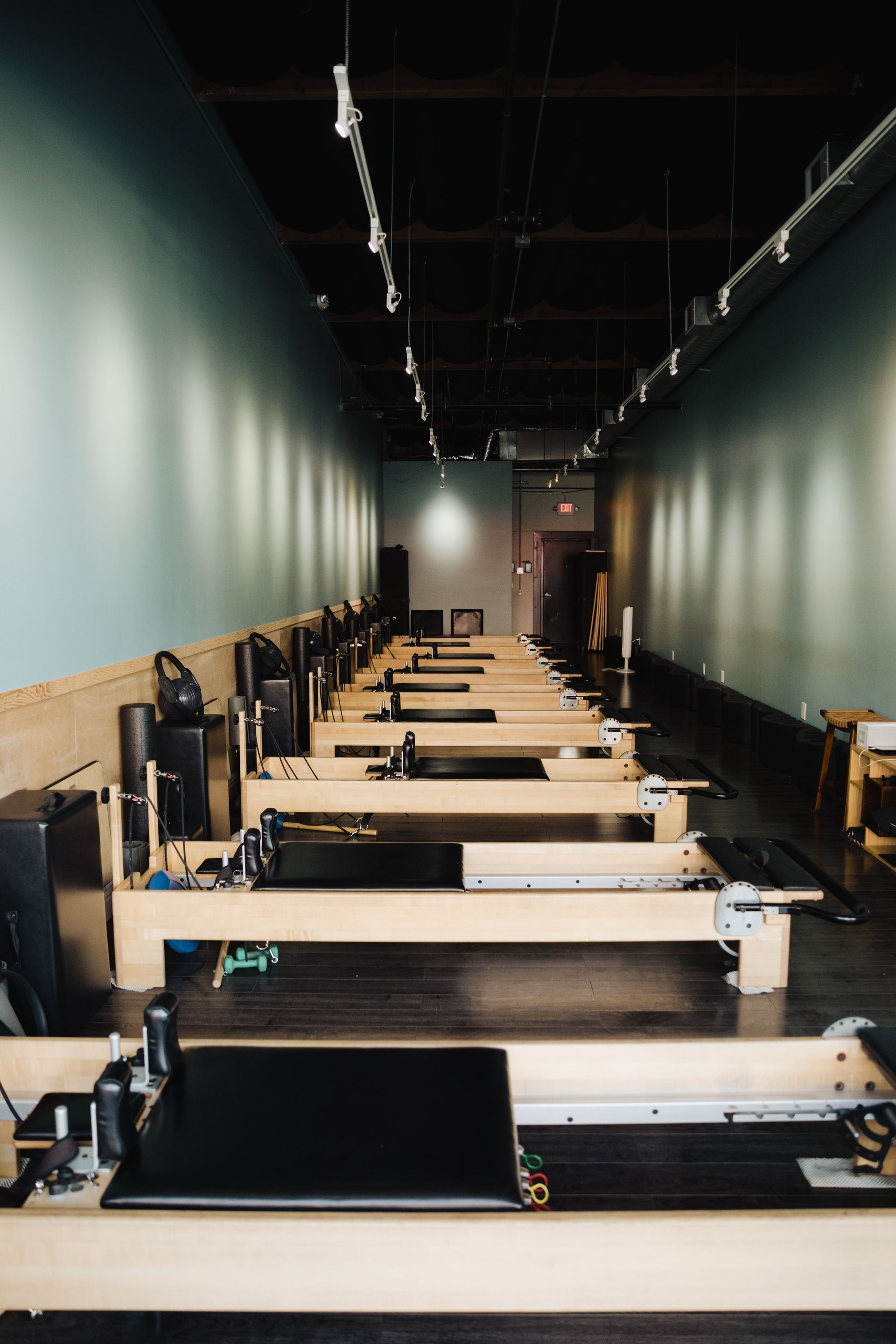 A row of pilates machines are lined up in a gym.