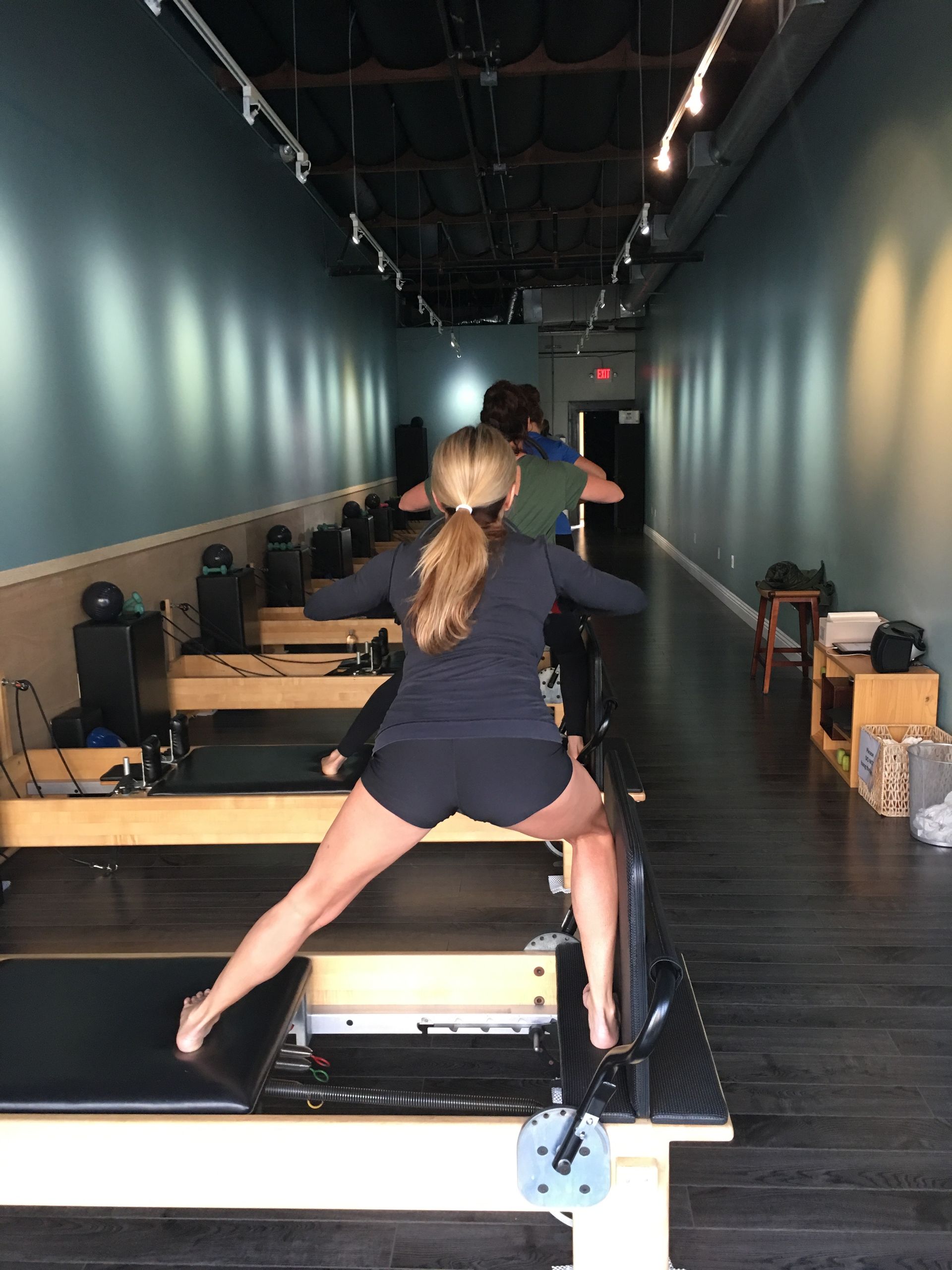 A woman is standing on a pilates machine in a gym.