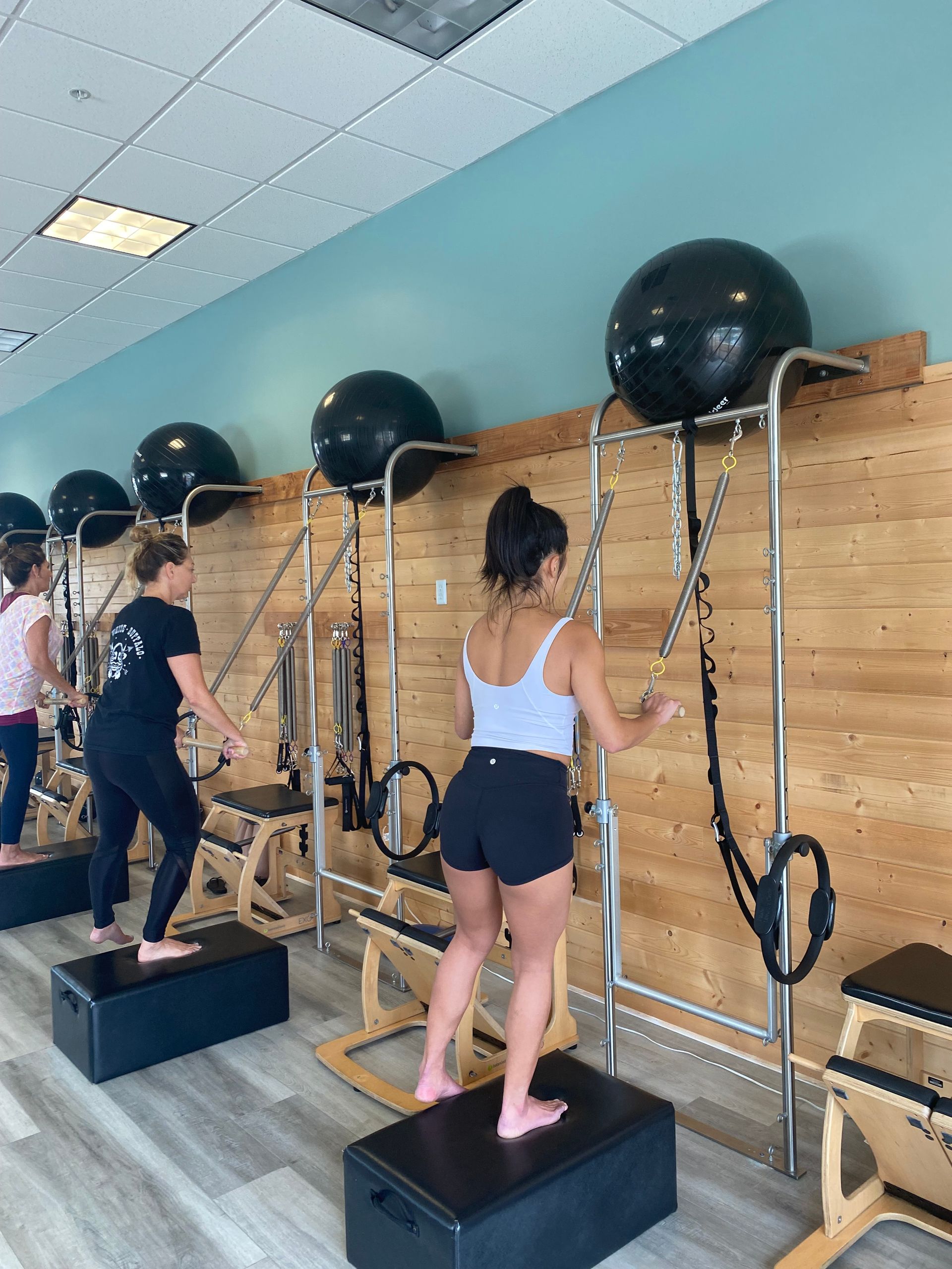 A group of people are doing pilates exercises in a gym.