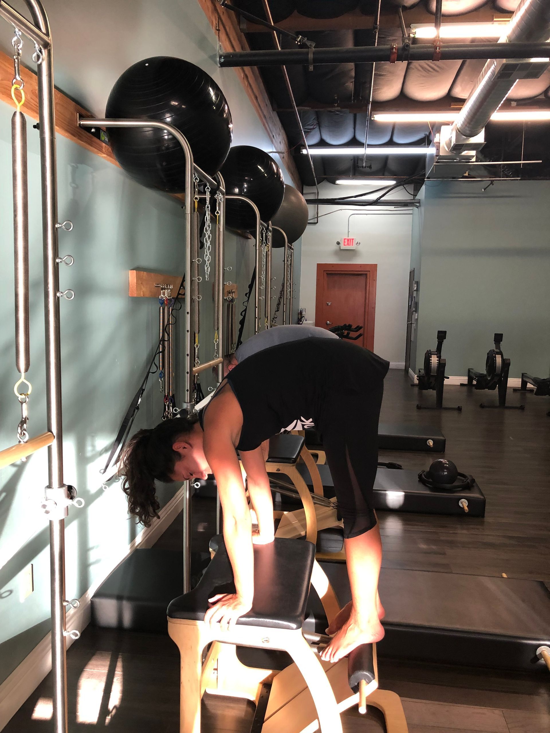 A woman is doing stretching exercises on a bench in a gym.