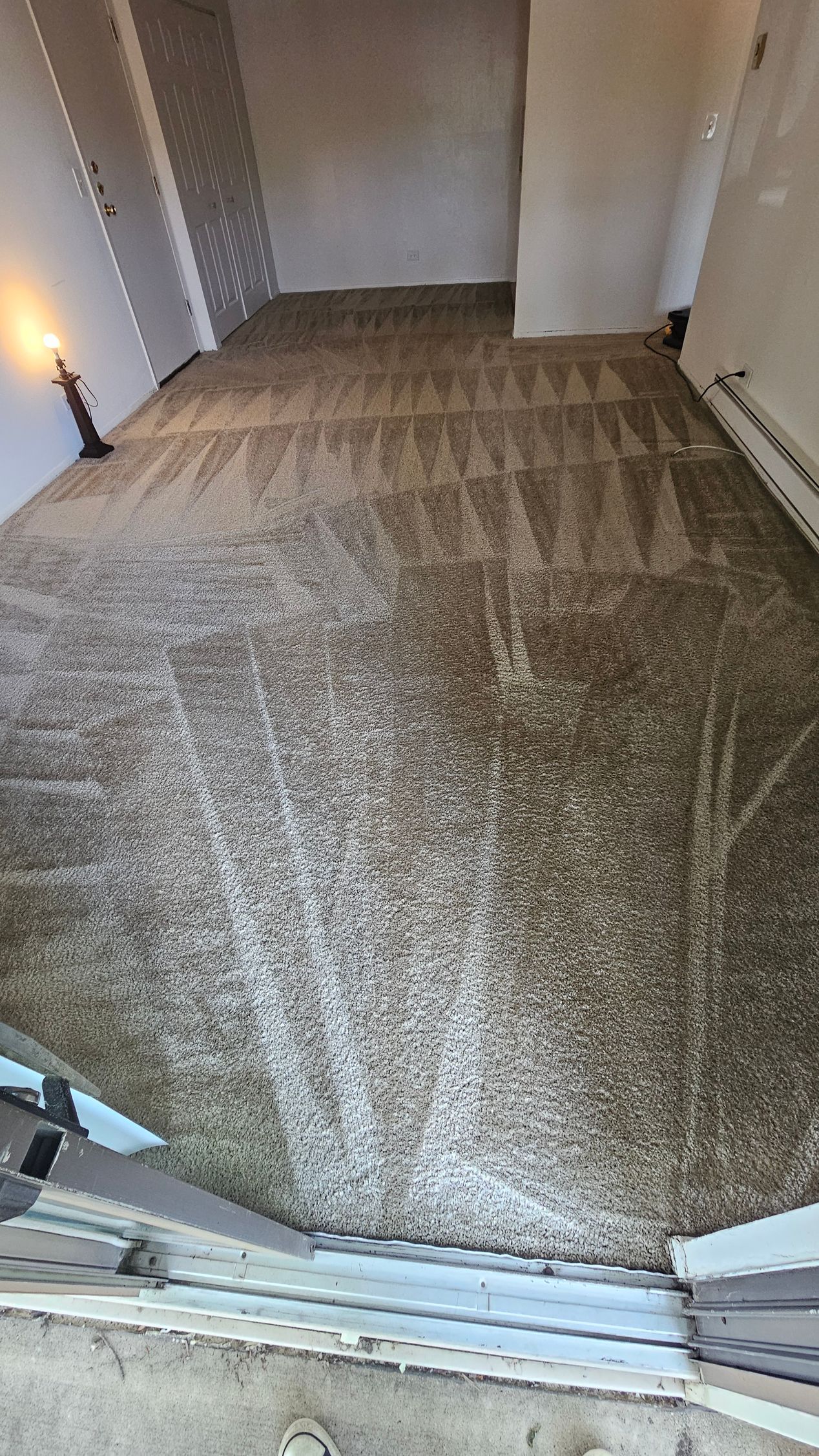Carpeted room with gray curtains, a candle on the left, and a window or door threshold in the foreground
