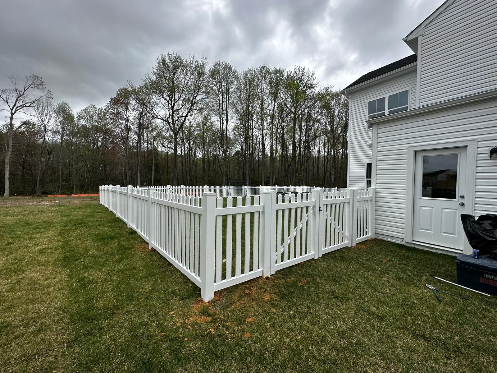 There is a white fence in the backyard of a house.