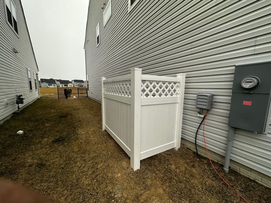 A white fence is sitting in the grass next to a house.