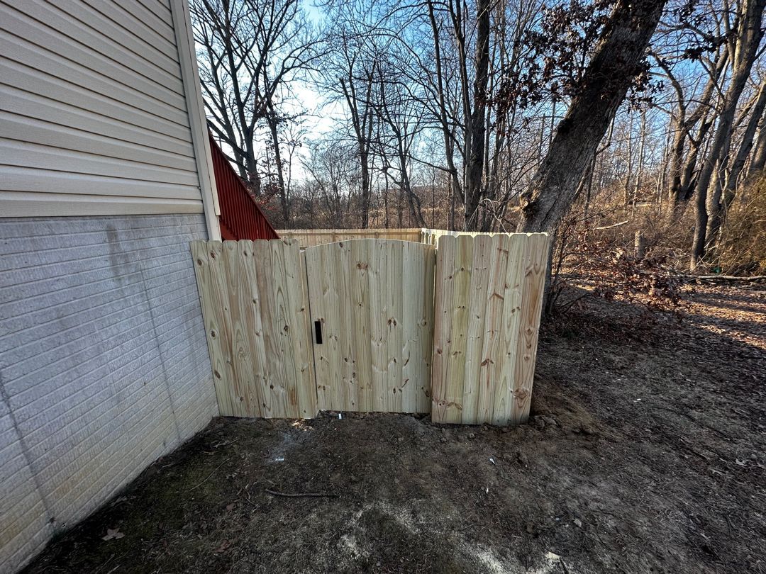 A wooden fence is sitting next to a house in the backyard.