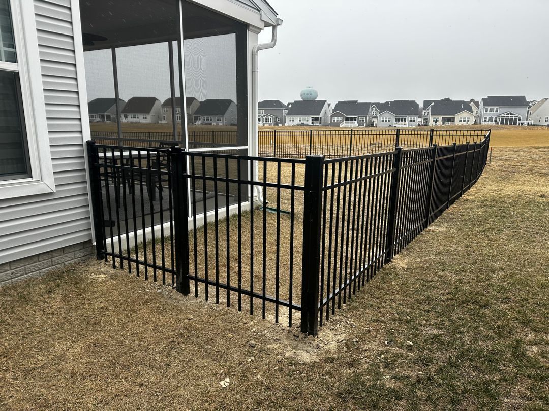 A black metal fence is surrounding a screened in porch.