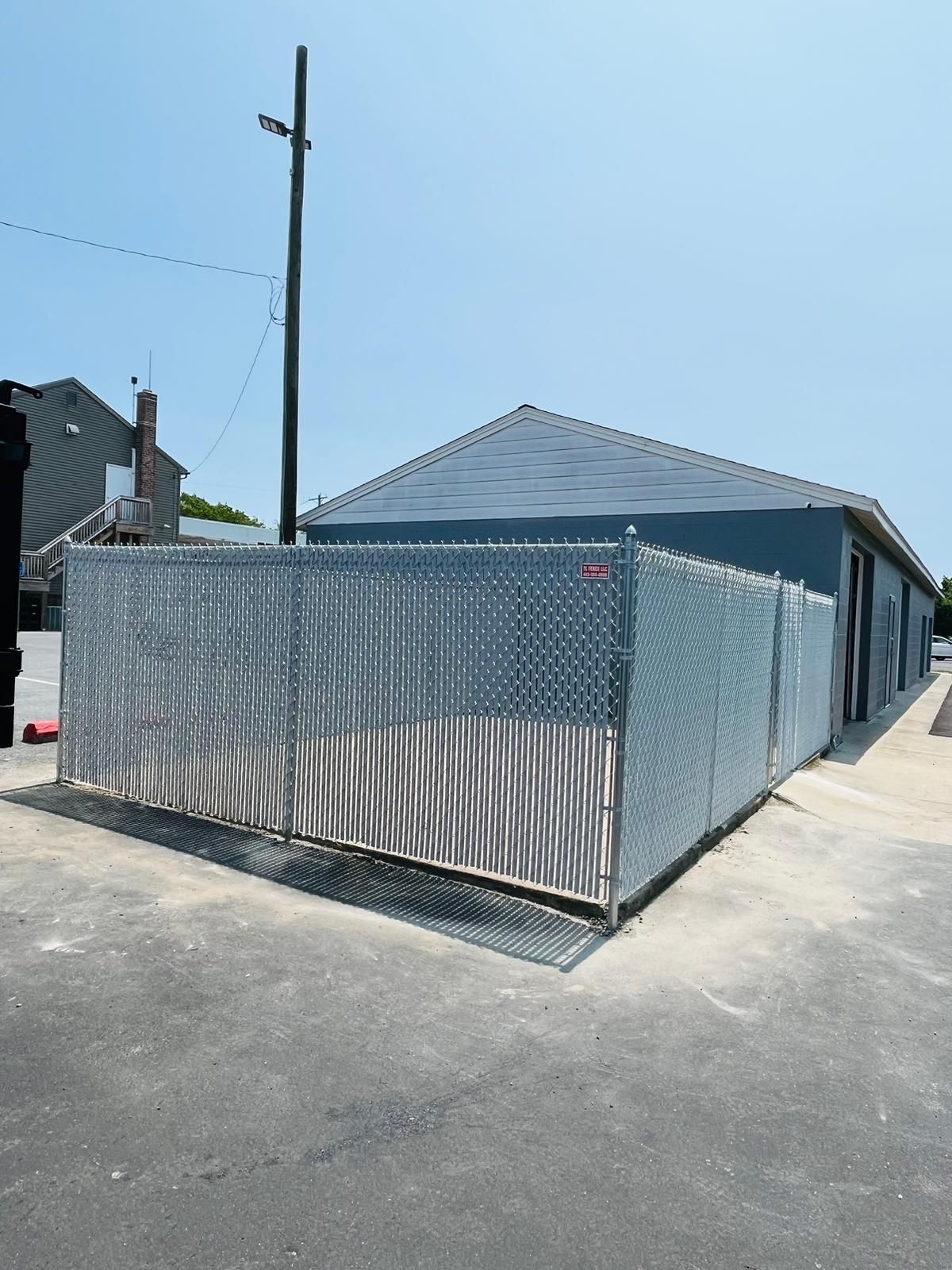 A chain link fence surrounds a building on a sunny day.