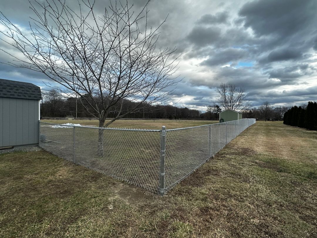 There is a chain link fence in the middle of a field.