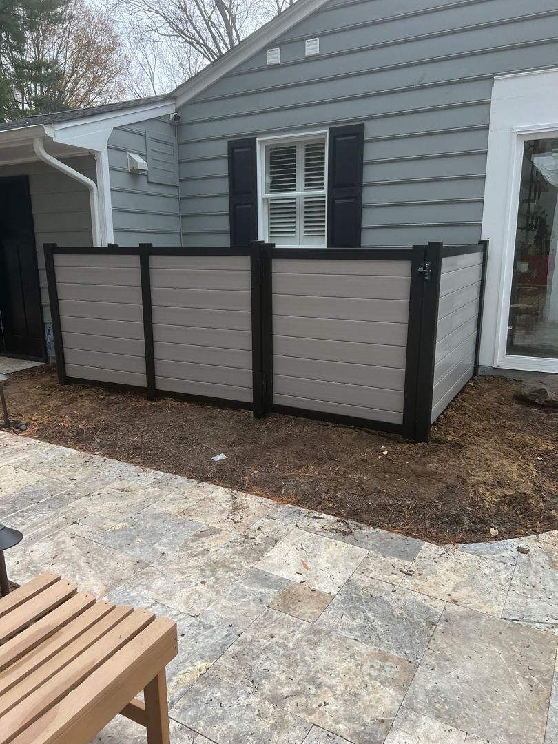A fence is sitting in front of a house next to a patio.