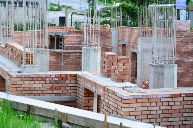 Partially built brick building foundation with concrete columns and exposed rebar at a construction site