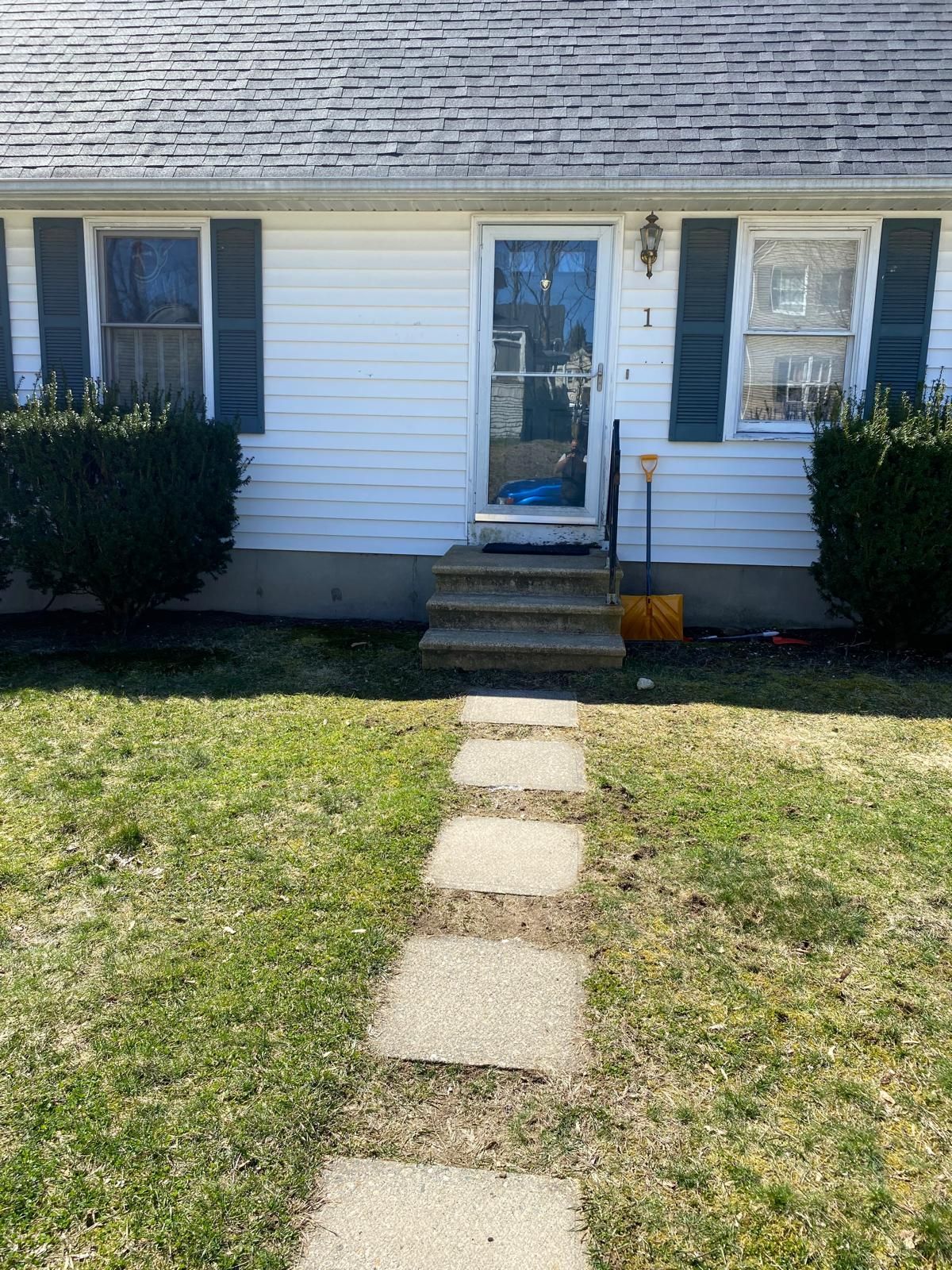 Front view of a small white house with a concrete stepping-stone path to the front door.