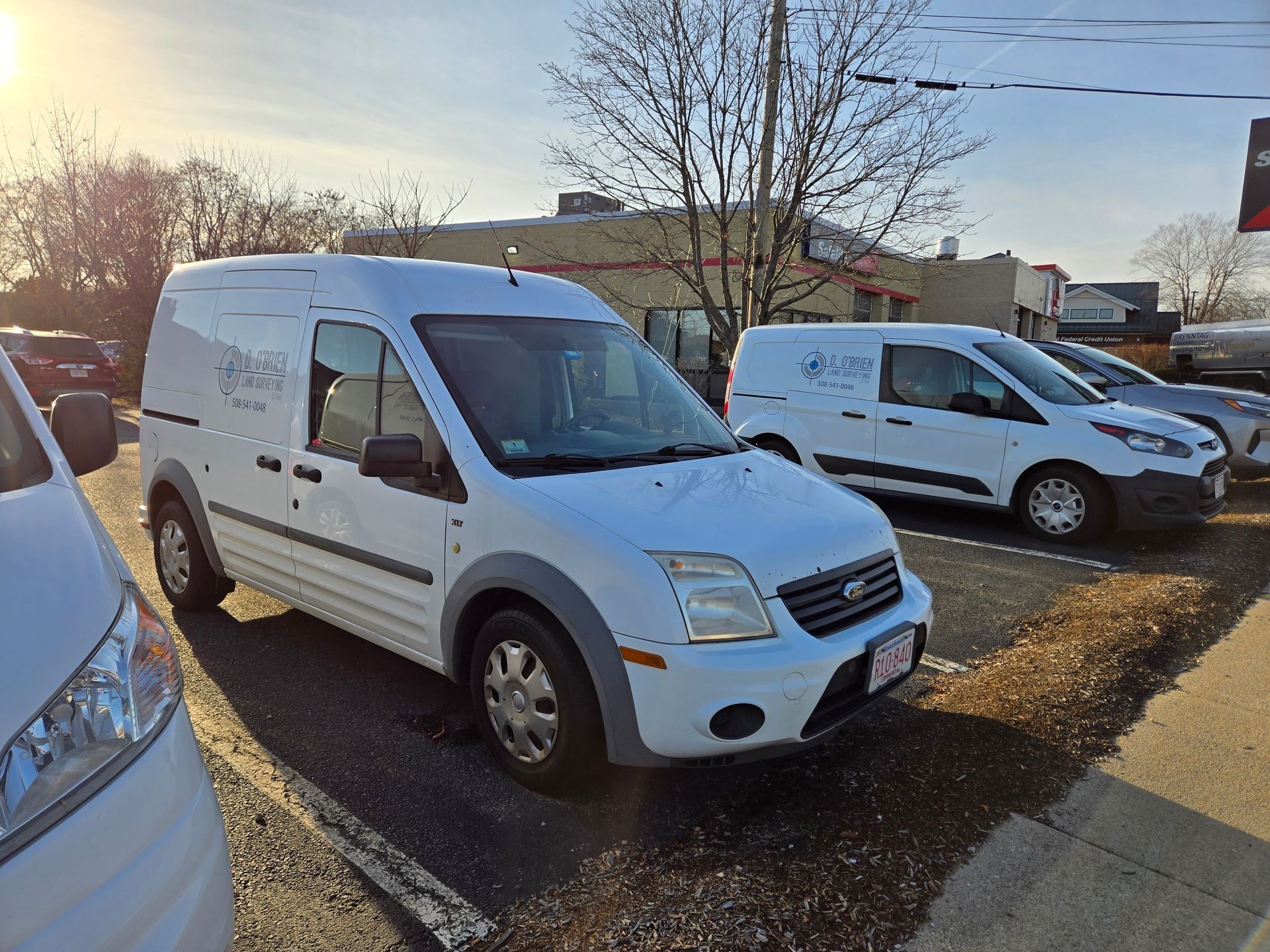 Three white Ford Transit Connect commercial vans parked in a row on a sunny day.