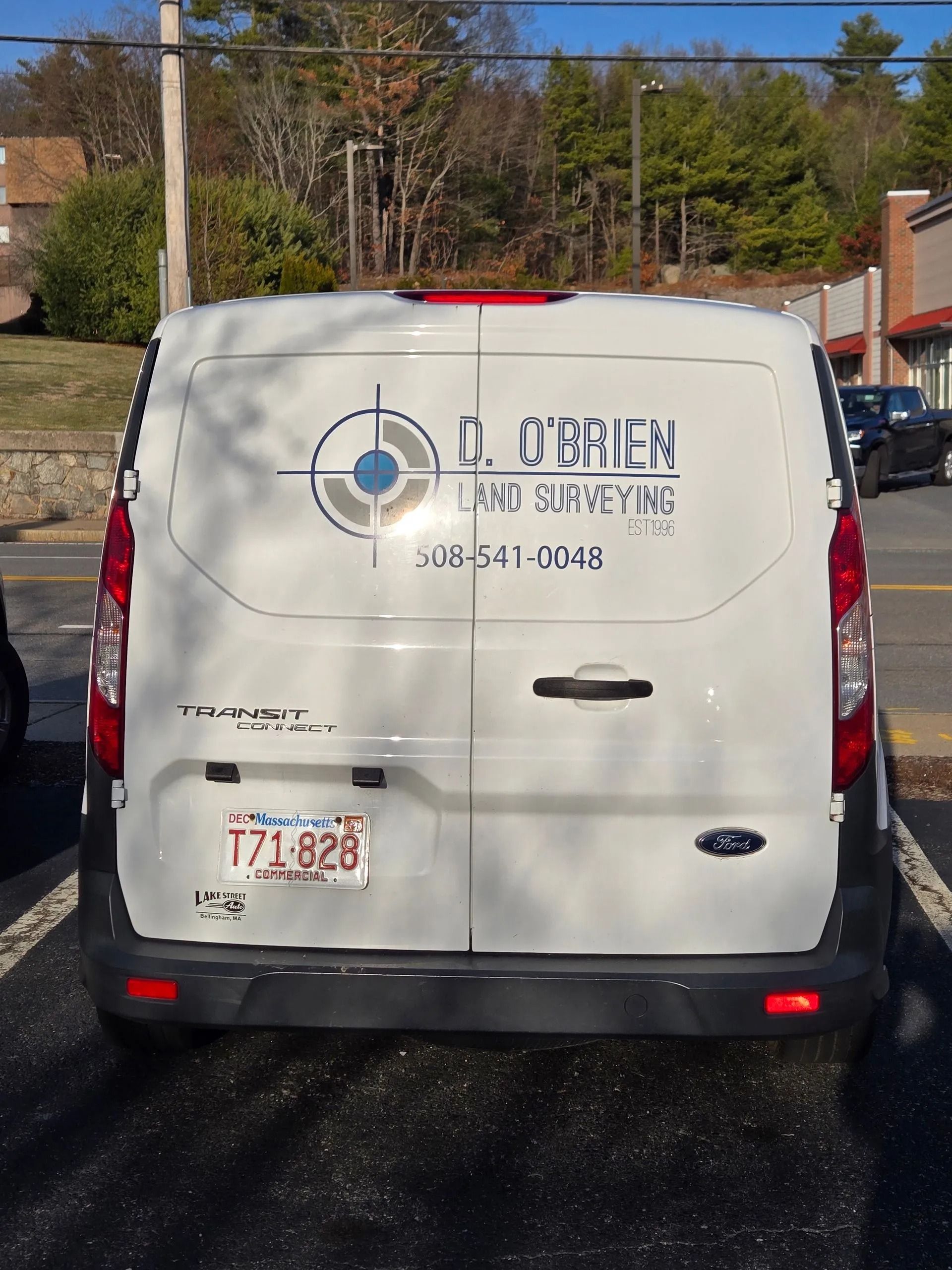 A white Ford Transit van parked in a lot, featuring a logo for 
