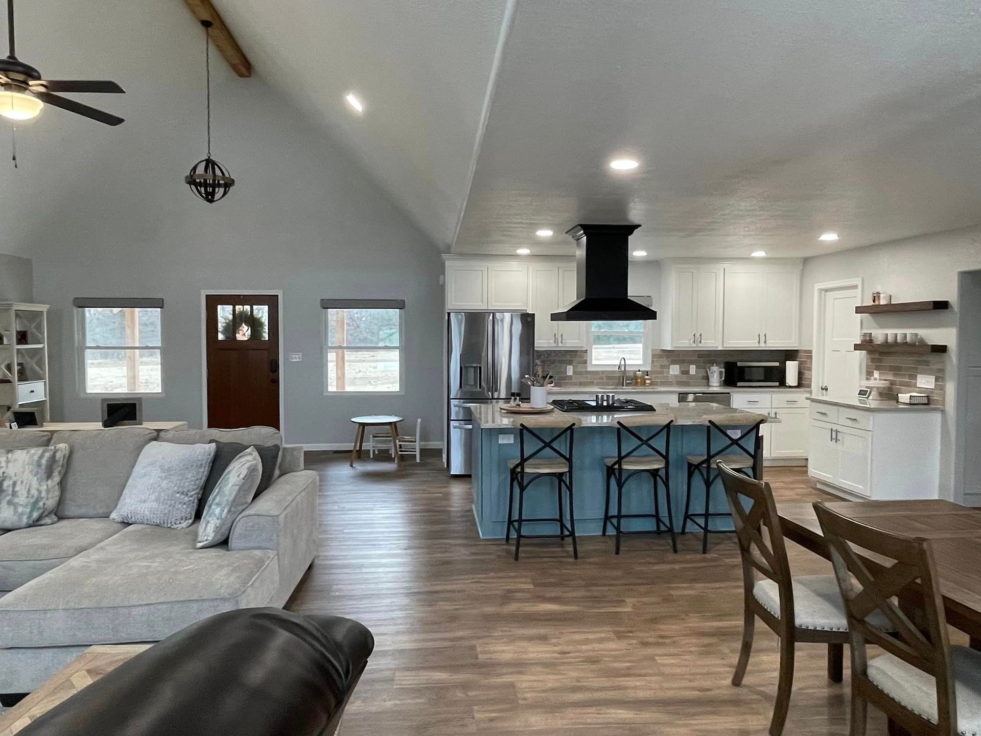 A living room with a couch, table, chairs and a kitchen.