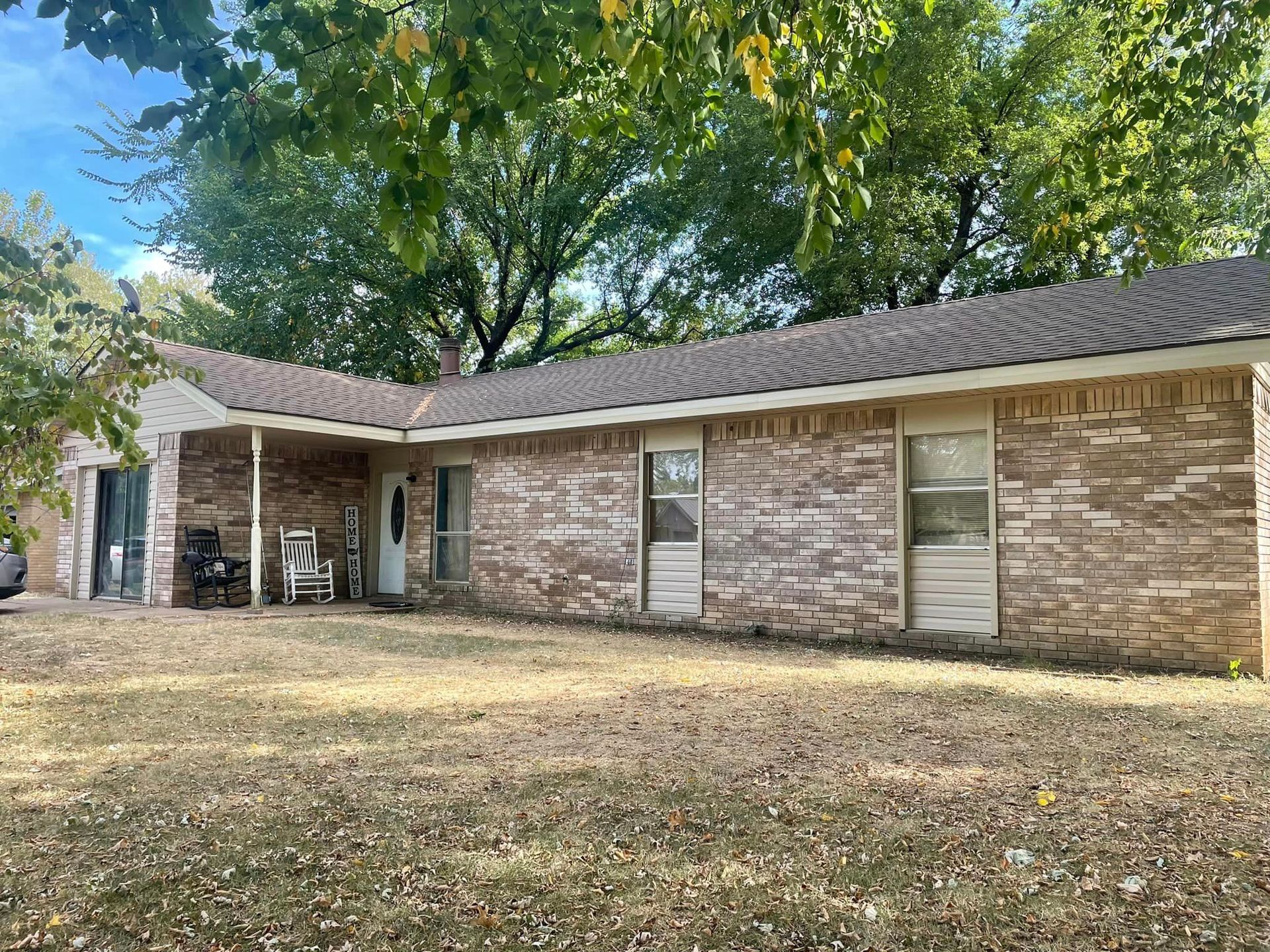 A brick house with a porch and a car parked in front of it