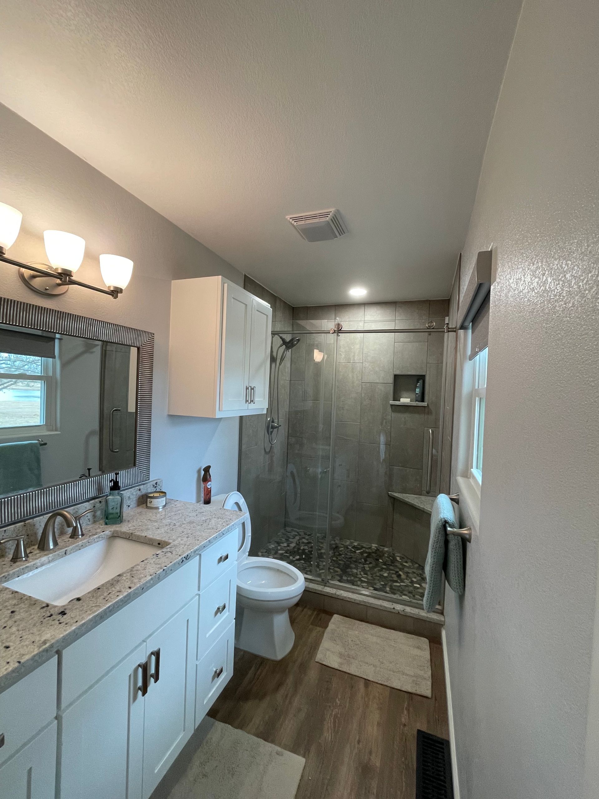 A bathroom with a sink, toilet, shower and mirror
