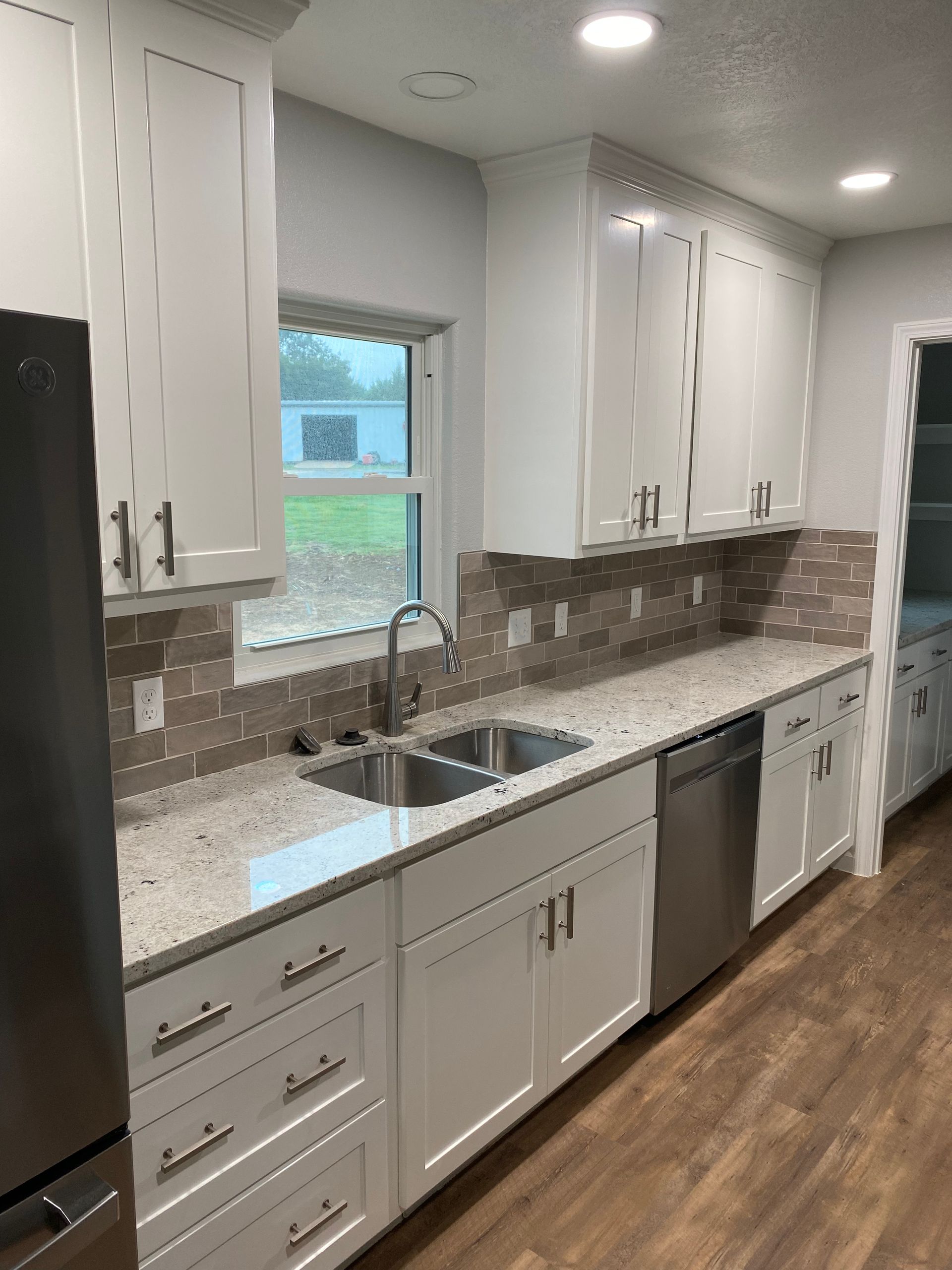 A kitchen with white cabinets , granite counter tops