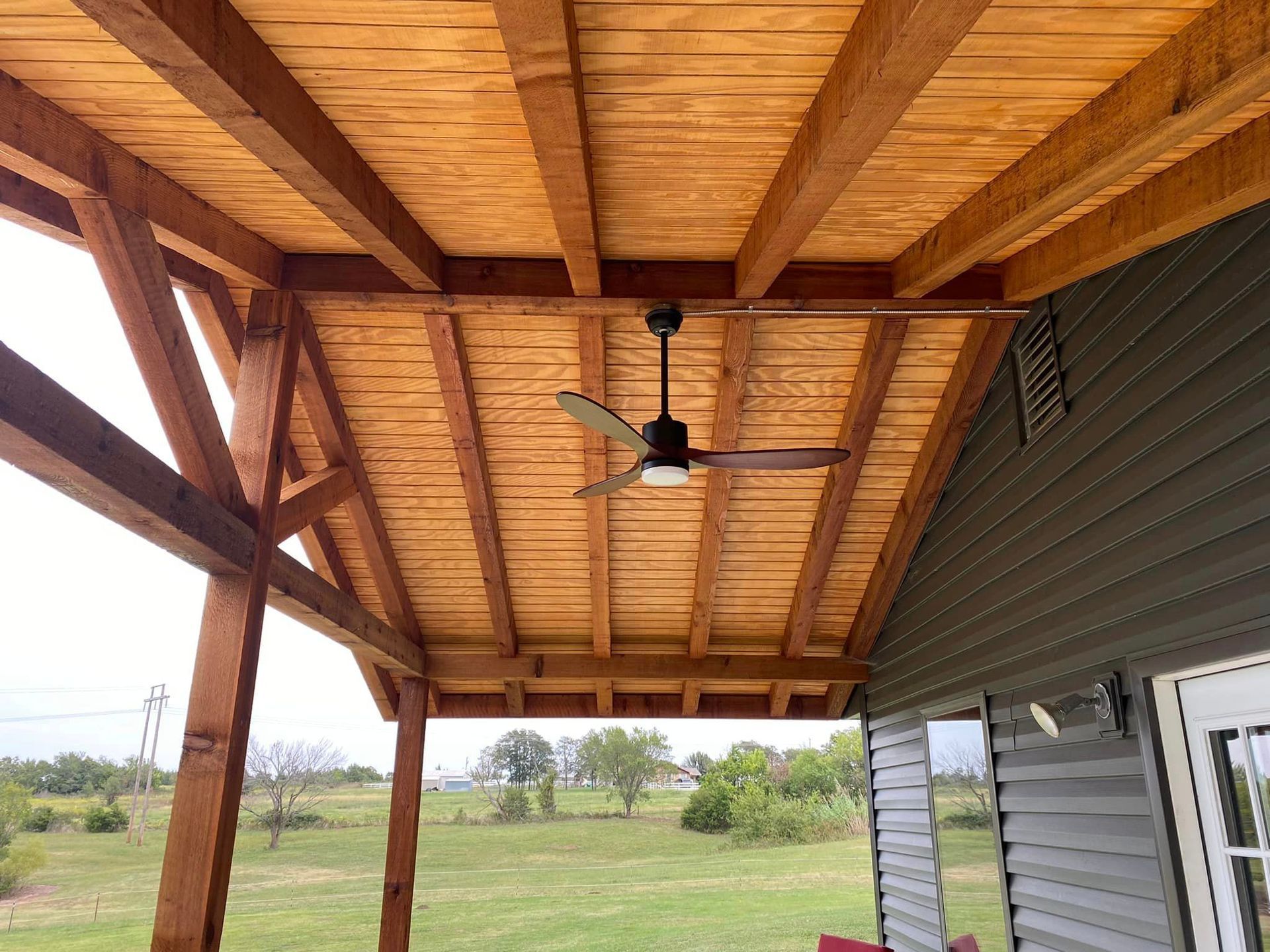 A ceiling fan is hanging from the ceiling of a wooden porch