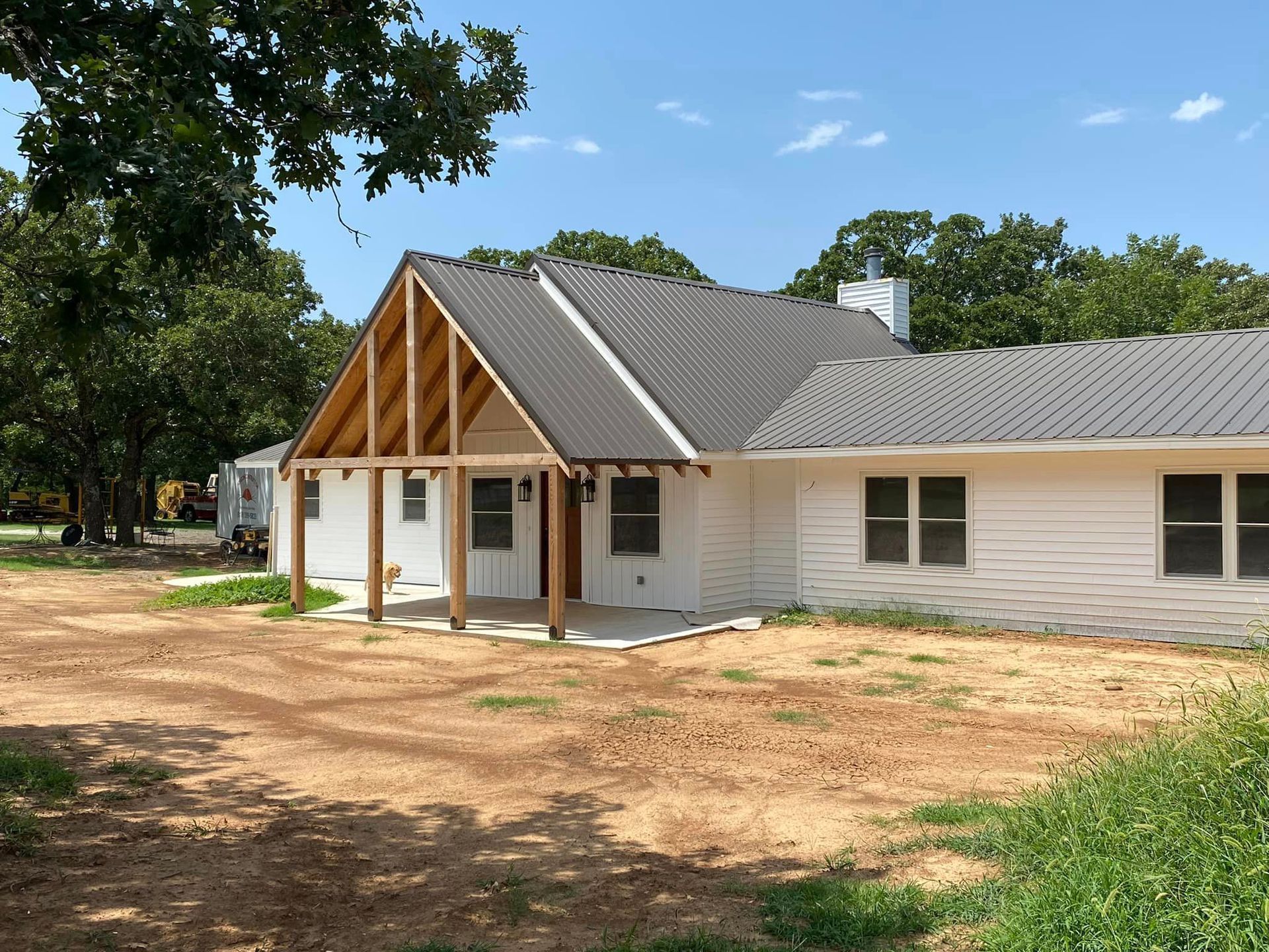 A white house with a metal roof and a wooden porch