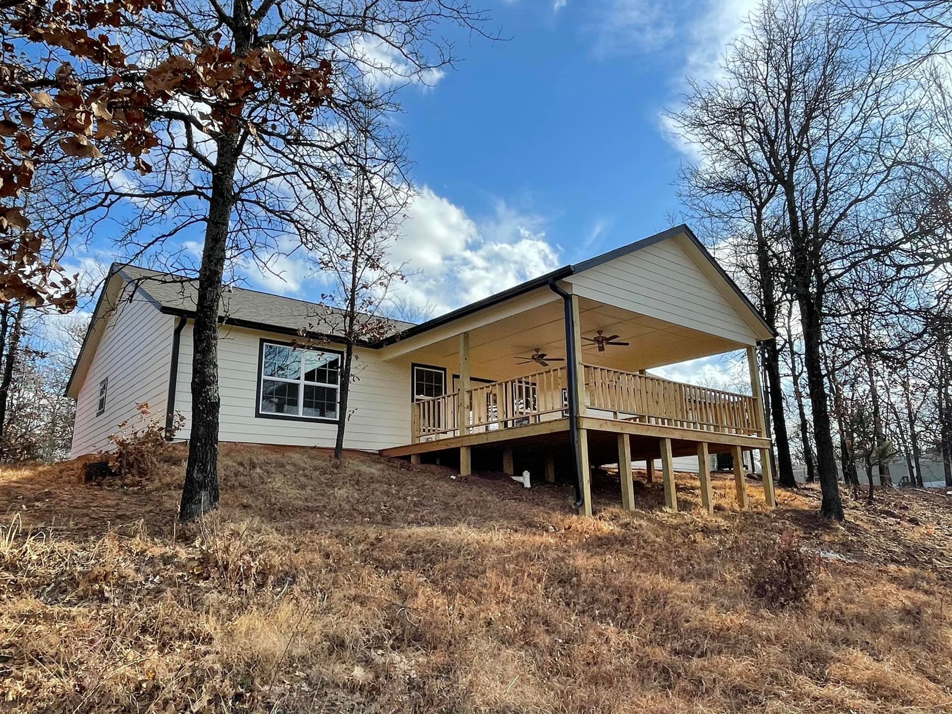 A white house with a large porch is sitting on top of a hill