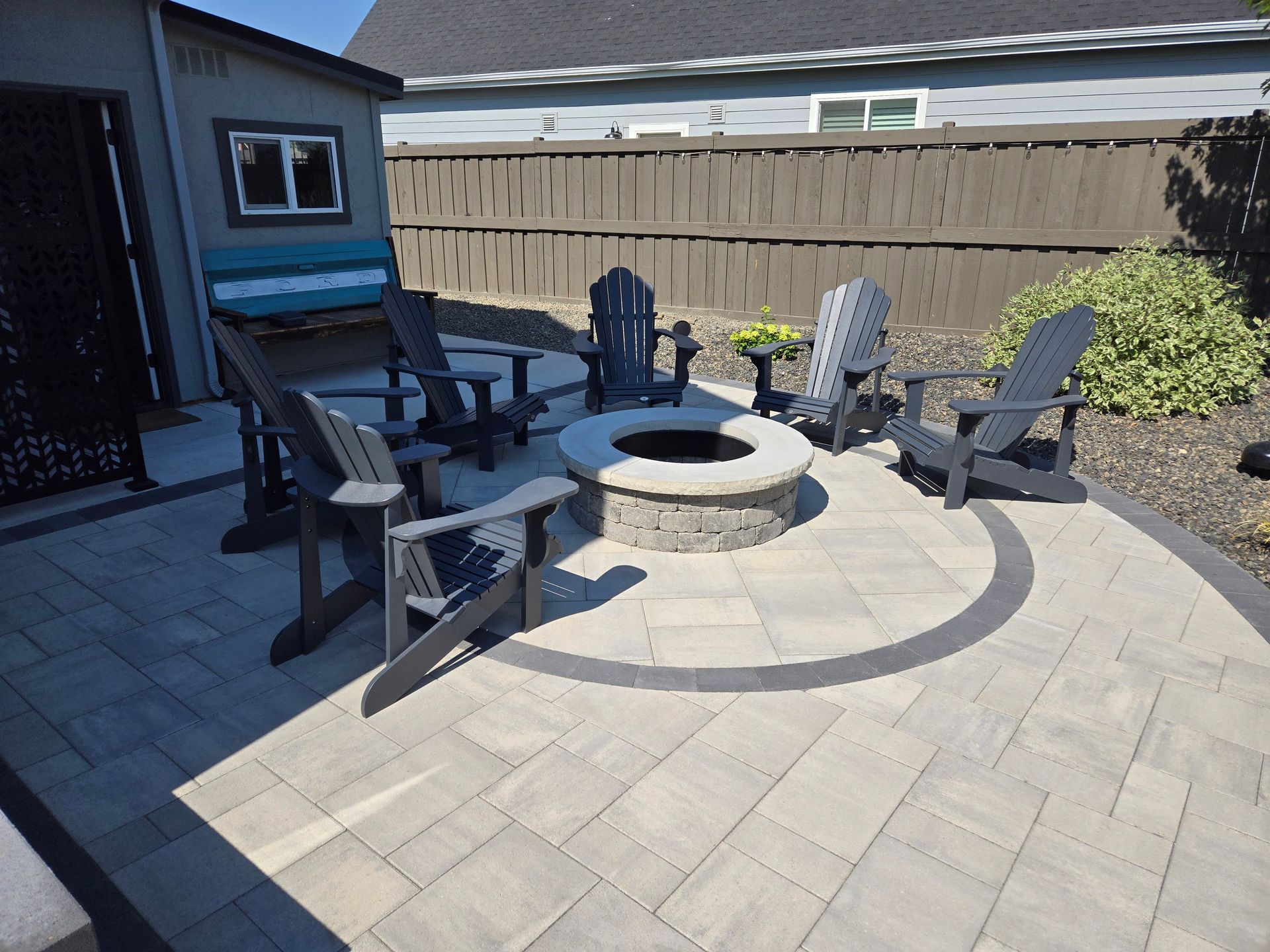 Patio with circular fire pit, Adirondack chairs, and a bench beside a house and fence
